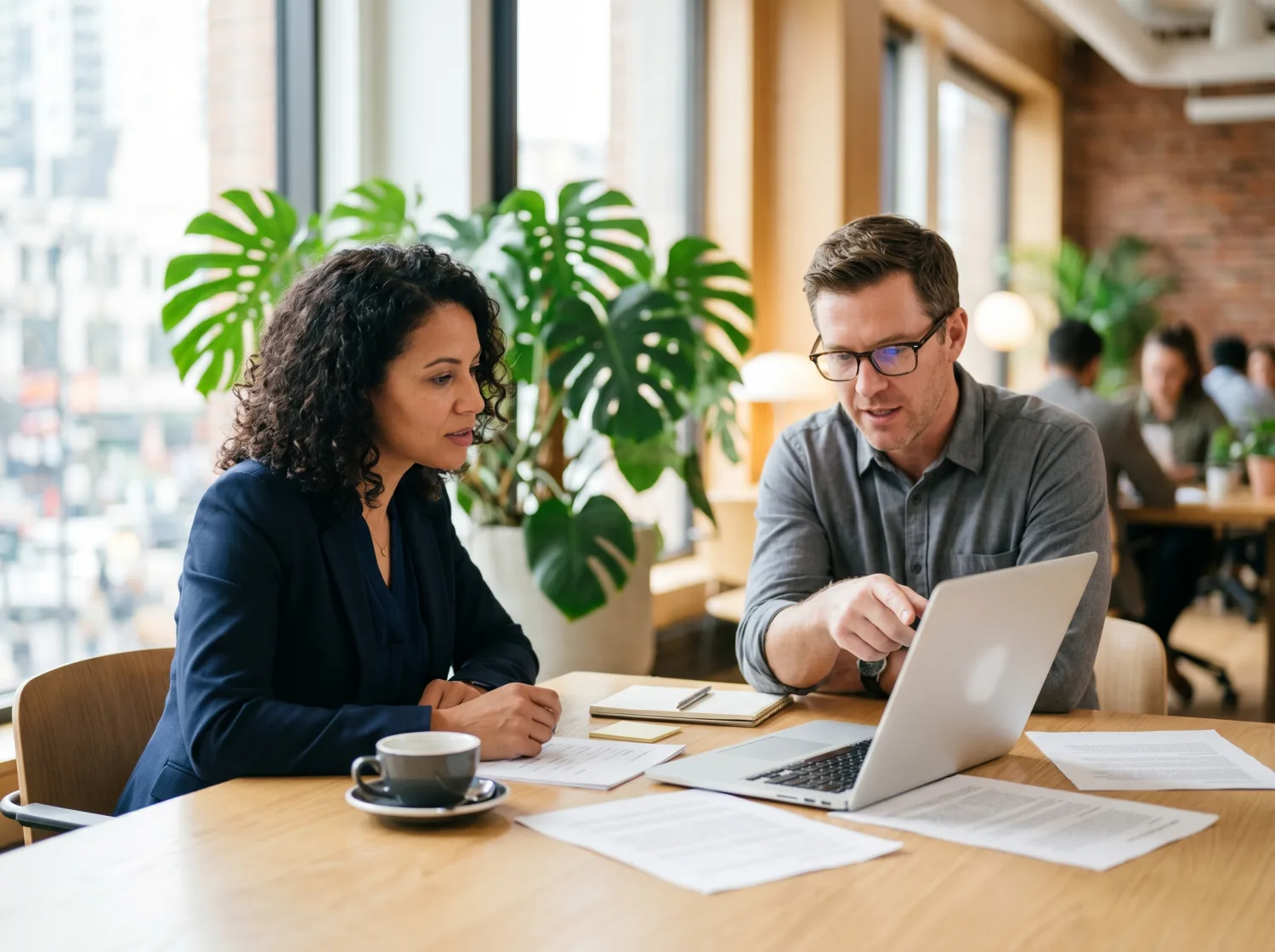 Two advisors reviewing an AI opportunity audit together at a desk with documents and a laptop